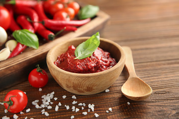 Delicious red sauce in bowl and ingredients on table