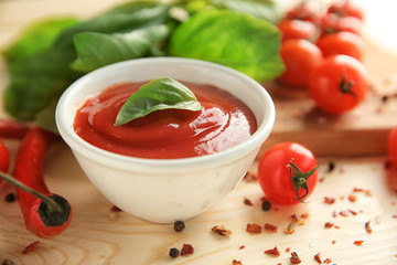 Delicious red sauce in bowl and ingredients on table