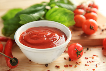 Delicious red sauce in bowl and ingredients on table