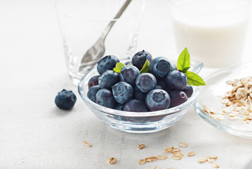 Bluberries in glass with oat flakes and milk for healthy breakfast