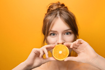 Beautiful funny young woman with citrus fruit on color background