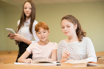 3 student girls are sitting at a Desk