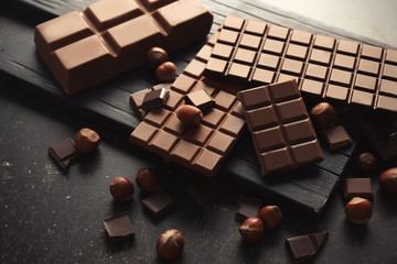 Tasty chocolate and hazelnuts on table