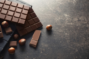 Tasty chocolate and hazelnuts on gray background, top view