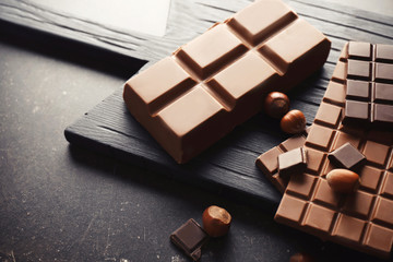 Tasty chocolate and hazelnuts on table