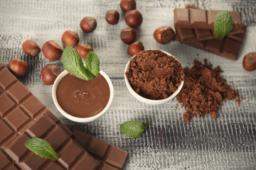 Composition with tasty chocolate and cocoa powder on wooden table