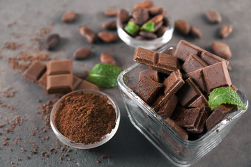 Bowls with tasty chocolate and cocoa powder on table