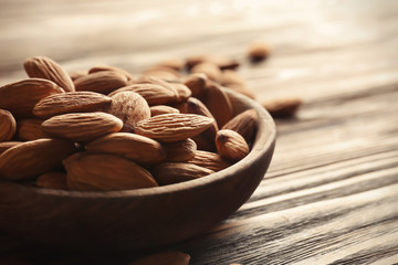 Bowl with almonds on wooden table, closeup