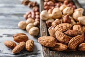 Wooden box with different nuts on table, closeup