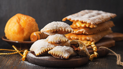carnival italian fritters bugie on dark wooden board.