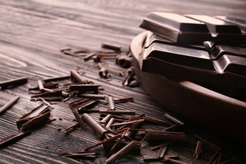 Plate with pieces of chocolate and curls on wooden table