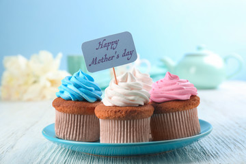 Tasty cupcakes and topper pick with words HAPPY MOTHER'S DAY on table