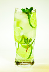 summer cold drink mojito lime and mint with ice and soda with drops on a glass on a white background