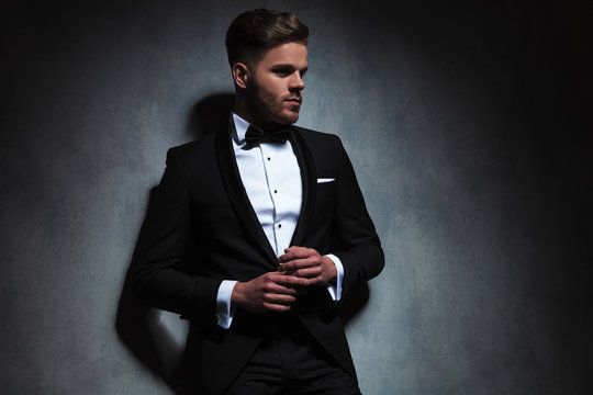 handsome unshaved man wearing black tuxedo looks to side