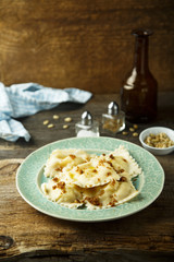 Homemade ravioli with fried bread crumbs, soft cheese and pine nuts