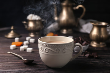 Cup of aromatic tea with milk on table
