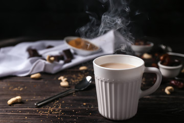 Cup of aromatic tea with milk on table