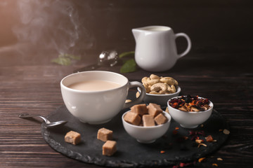 Cup of aromatic tea with milk on slate plate