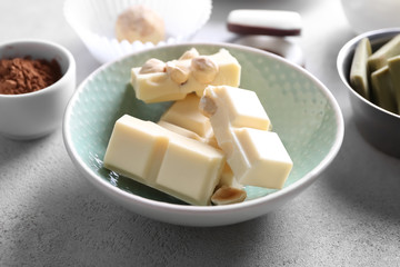 Bowl with pieces of white chocolate on table