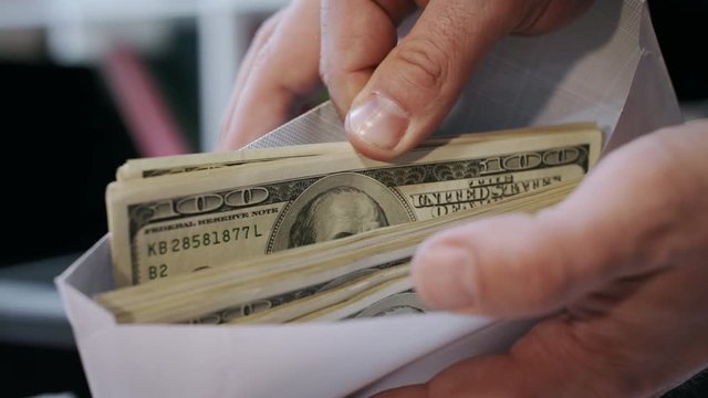 Close up of cash money in envelope in hands. Money bonus in paper envelope. Man holding envelope with dollar bills. World bribery. Scam and corruption concept. Credit company financial services