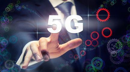 A businessman pressing a 5G business concept on a graphical display of cogs
