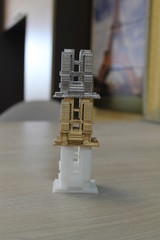 the model of the house is printed on a 3d printer. 3 models of white, gold and silver color standing on each other.