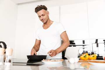 Fototapeta na wymiar Attractive man cooking eggs for breakfast