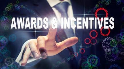 A businessman pressing a Awards and Incentives business concept on a graphical display of cogs