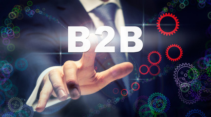 A businessman pressing a B2B business concept on a graphical display of cogs