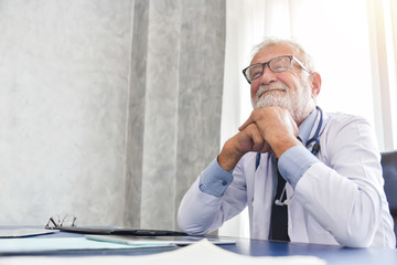 Senior male Doctor is smiling in a medical room.