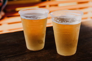 Two plastic glasses with beer stand side by side