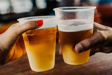 Hand of man and woman holding glasses with beer