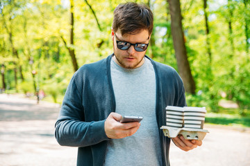 Fototapeta premium man holding coffee and phone. walking by city park. drink to go