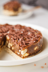 Raw vegan chocolate cake with nuts and chocolate in white plate. Healthy vegan food concept.