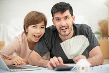 Happy couple holding money and calculating their budget.