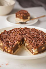 Fototapeta na wymiar Raw vegan chocolate cake with nuts and chocolate in white plate. Healthy vegan food concept.