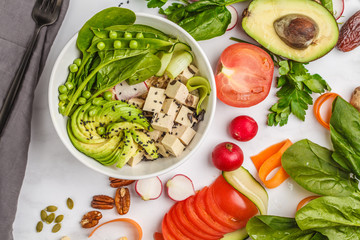 Buddha bowl with tofu, rice, avocado and vegetables. Healthy vegan food concept.