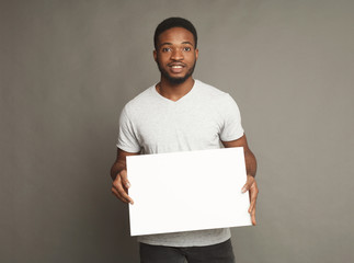 Picture of young african-american man holding white blank board