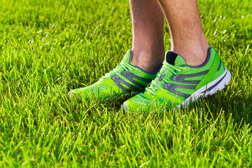 Sports shoes sneakers on a fresh green grass field. Sport equipment bottom view. Sports in the open air.