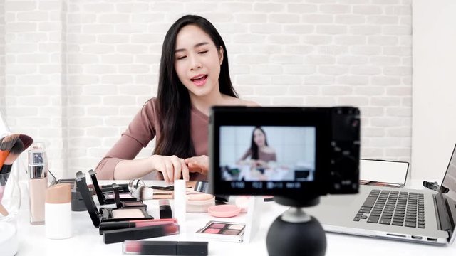 Young beautiful Asian woman professional beauty vlogger or blogger sharing a make up tutorial video online