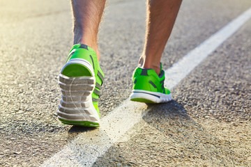 Runner man feet running on road closeup on shoe. Male fitness athlete jogger workout in wellness...