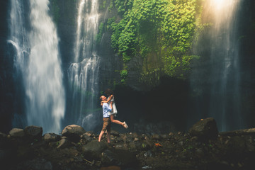 Amazing romantic view of happy couple near beautiful grand waterfall