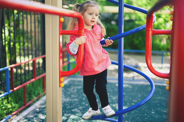 Climbing little girl at playground. Playground outdoor in summer time