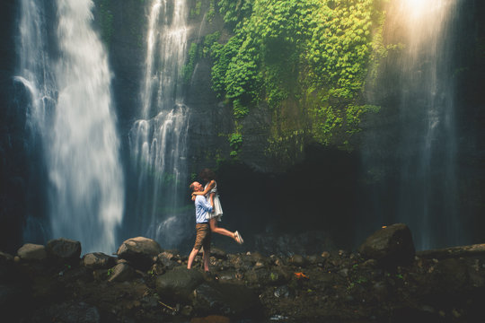 Amazing romantic view of happy couple near beautiful grand waterfall
