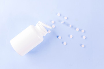 Medical and healthcare concept - different shape pills, thermometer on blue background, top view