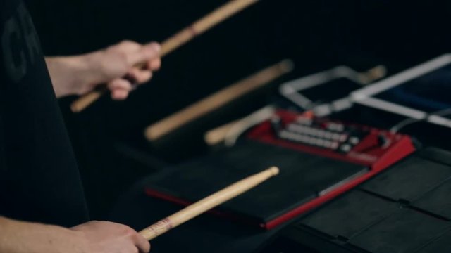 Close up shot of man's hands drum sticks on sampler and electronic pads
