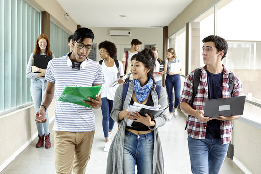 Students chatting while walking together in school corridor