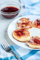 Cottage cheese pancakes with sour cream and strawberry jam on white background, breakfast or lunch