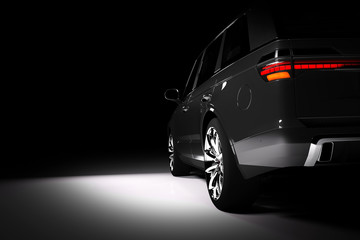 Back view of modern black SUV car in a spotlight