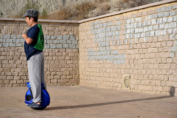 A young boy riding a mono wheel in the natural park of Mount Ifach on the Mediterranean coast in Calpe Spain